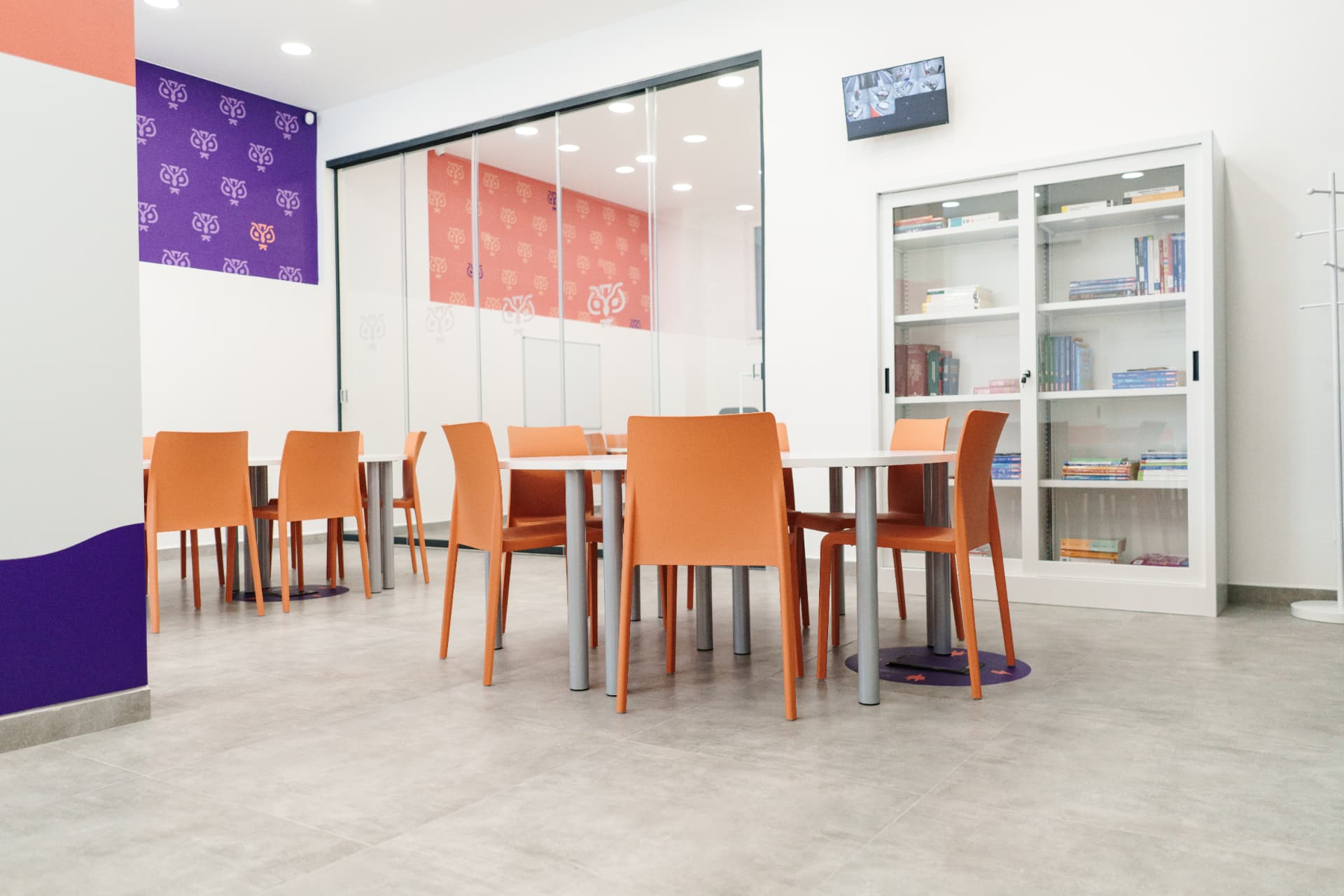 Sala studio con libreria, tavoli e pareti decorate con il gufo Paikos