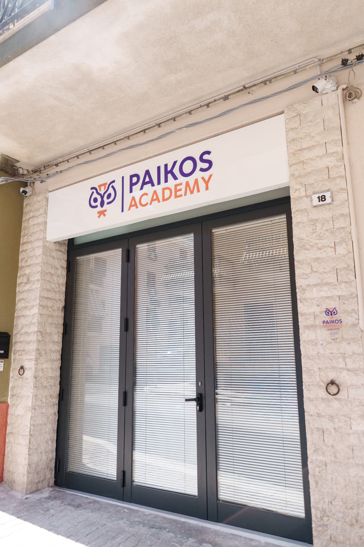 Ingresso di Paikos Academy in Via Lombardia 18 a Capaci con insegna viola e arancione
